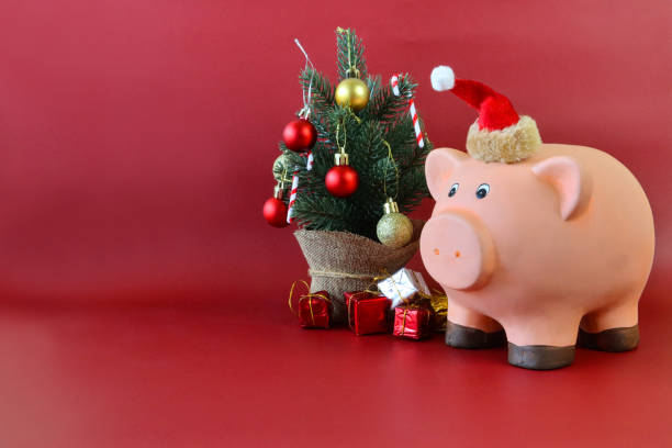 キャンディー杖、赤と金のボーブル、箔包装された贈り物、赤い背景、コピースペース、クリスマス予算、手形、借金、財政コンセプトで飾られたミニトウヒクリスマスツリーのそばに立っ� - focus on foreground tax close up finance ストックフォトと画像