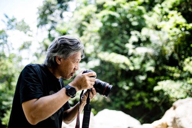 istock senior Asian photographer standing in jungle 1357687814