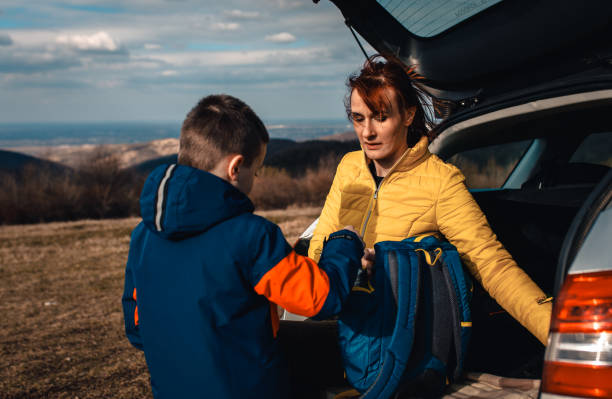 istock Mother and son take break from driving sitting by the car while drinking tea in nature. 1357689130