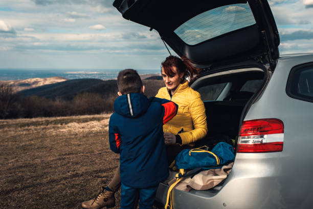 istock Mother and son take break from driving sitting by the car while drinking tea in nature. 1357690131