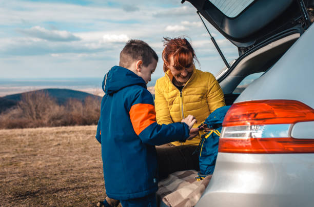 istock Mother and son take break from driving sitting by the car while drinking tea in nature. 1357690361