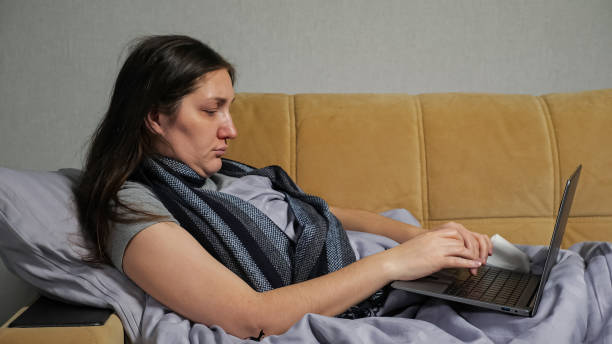 istock Sick woman with runny nose works distantly using laptop 1357690965