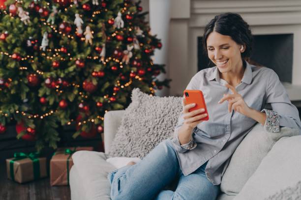 happy female in earbuds holding smartphone, talking with family or friends online at christmas time - spanish culture audio imagens e fotografias de stock