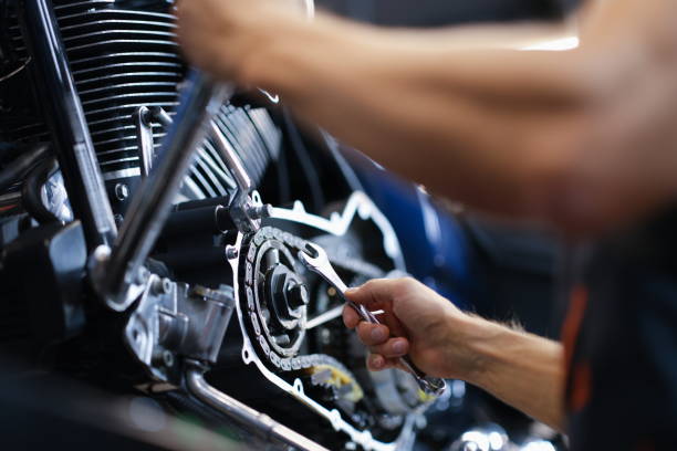 Master repairman repairing motorcycle with wrench closeup stock photo