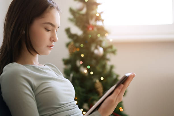 adolescente utilisant une tablette sur fond de sapin de noël - tree house audio photos et images de collection