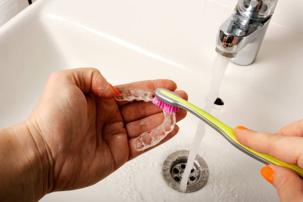 Cleaning of retention mouth guards with toothbrush stock photo