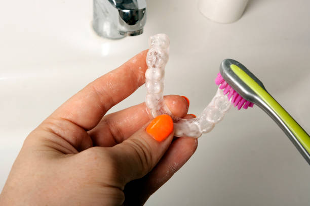 Cleaning of retention mouth guards with toothbrush stock photo