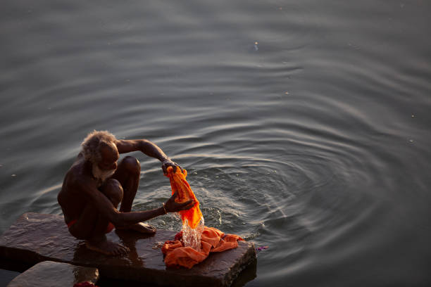 anciano hindú lavando ropa en el río ganges, varanasi, india - caste system fotografías e imágenes de stock