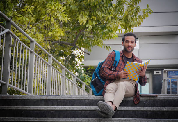 istock A young college student at college campus trying to read his book 1357697308