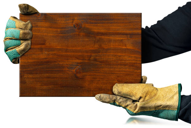 Carpenter Holding a Brown Wooden Plank Isolated on White Background Carpenter with protective work gloves holding a brown wooden plank isolated on white background. cutting board plank wood isolated stock pictures, royalty-free photos & images