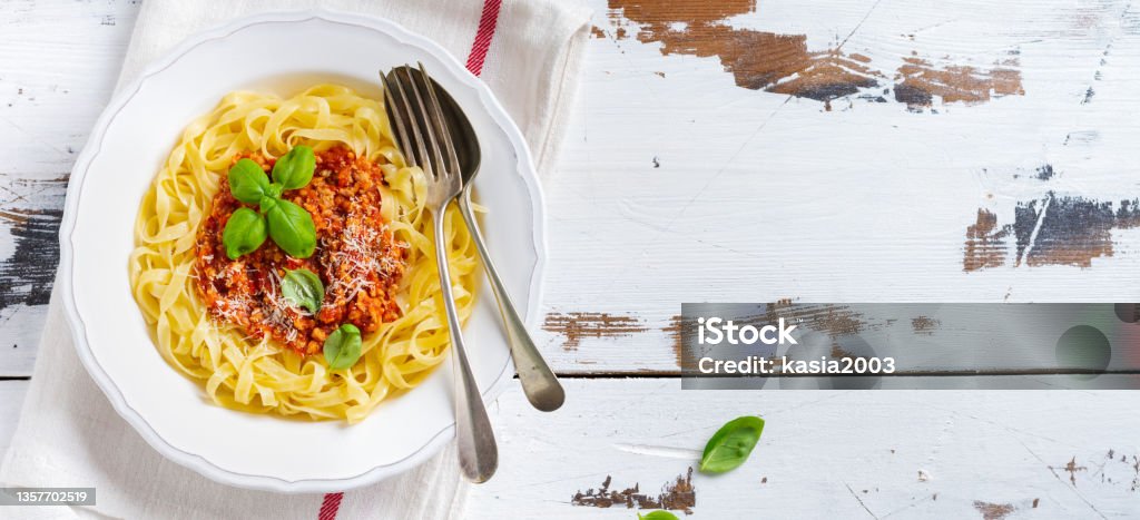 Fettuccine pasta with traditional Italian Passat sauce and parmesan cheese in white plate on white old wooden background. Top view. Bolognese Sauce Stock Photo