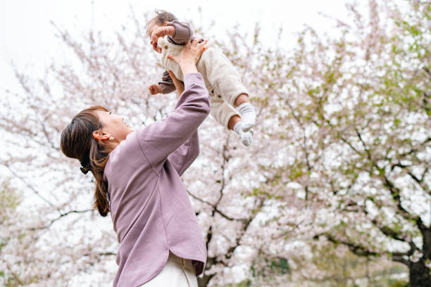 istock Mother and her small daughter enjoying their time during spring time sakura cherry blossom trees season in nature 1357703639