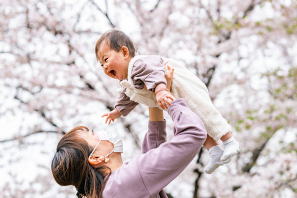istock Mother and her small daughter enjoying their time during spring time sakura cherry blossom trees season in nature 1357705723