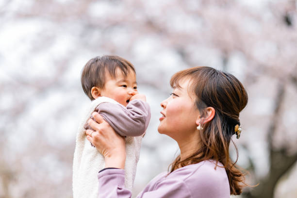 istock Mother and her small daughter enjoying their time during spring time sakura cherry blossom trees season in nature 1357706185