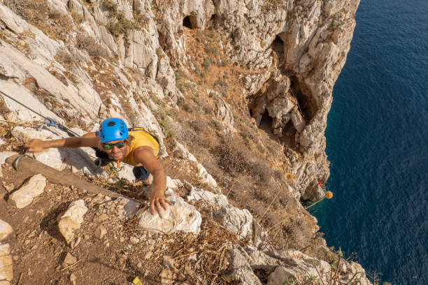 istock High angle view of rock climber moving forward, he climbs above the sea 1357708994