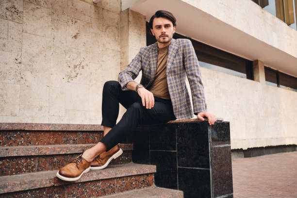 istock Young handsome stylish man in checkered jacket confidently looking in camera outdoor 1357710123