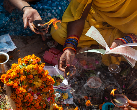 Varanasi, India - April 8, 2010: Hindu woman reading Hinduism holy texts and offering marigold flowers for puja ceremony in temple Varanasi, India.