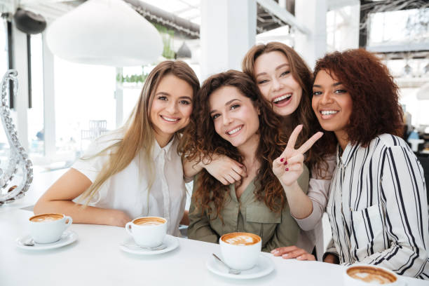 istock Four pretty happy friends sitting in cafe 1357720220