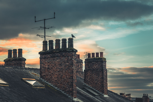 White smoke from a brick chimney against the background of tiled roofs in a horizontal format