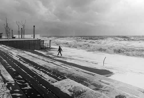 Young man watching huge waves on the Konyaalti Beach on a stormy day Antalya, Turkey