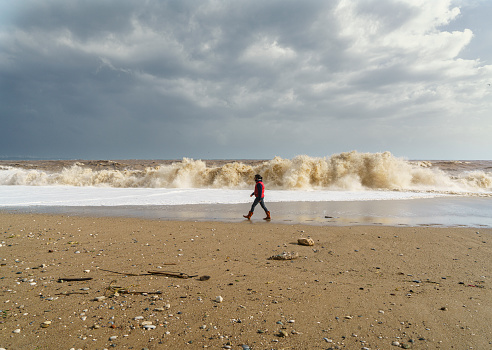 Young man walking on the Konyaalti Beach on a stormy day Antalya, Turkey