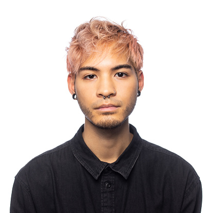 Young man with pink hair being photographed in front of a white background in a photo studio