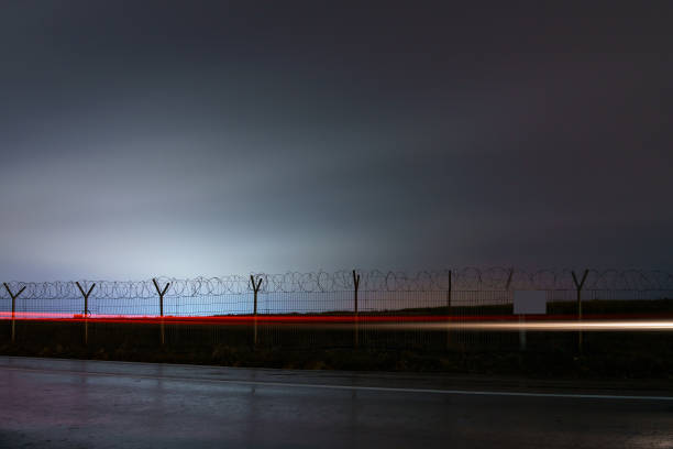 Protected area fence with barbed wire in the dark of night. Background with copy space Protected area fence with barbed wire in the dark of night. Background with copy space for text prison escape stock pictures, royalty-free photos & images