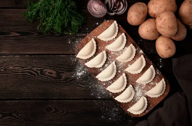 Traditional Polish dish, dumplings with potatoes, raw, frozen, on a wooden table, top view, with ingredients, no people,