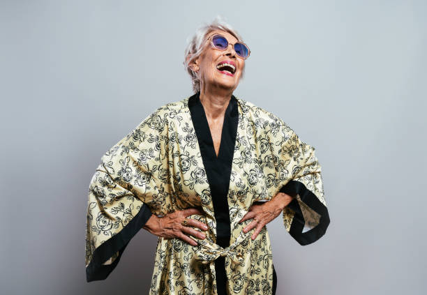 beautiful and elegant old influencer woman. Cool grandmother posing in studio wearing fashionable clothes. Happy senior lady celebrating and making party. Concept about seniority and lifestyle