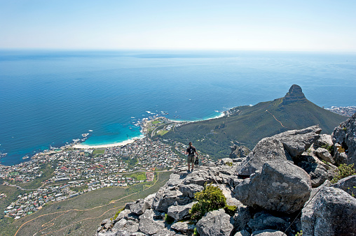 Precarious perch, Table Mountain overlooking Cape Town, Cape Peninsula, South Africa. South Africa on the southern tip of Africa is a beautiful, colourful and diverse country of varied landscapes from craggy rocky cliffs and coastline to savannah grasses of the natural wildlife parks that reflect the chequered social history and social issues of the country.