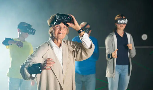 Photo of Grandparents with grandchildren in virtual reality glasses in quest room