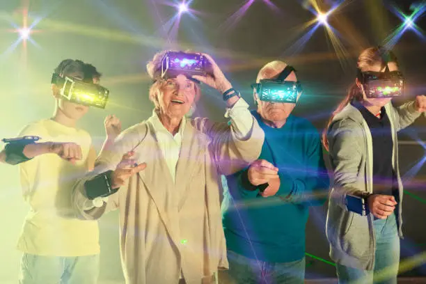 Photo of Grandparents with grandchildren in virtual reality glasses in quest room