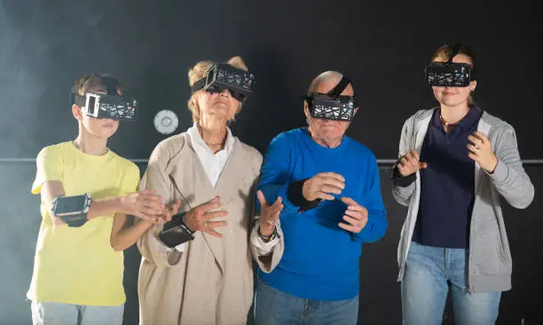 Photo of Grandparents with grandchildren in virtual reality glasses in quest room