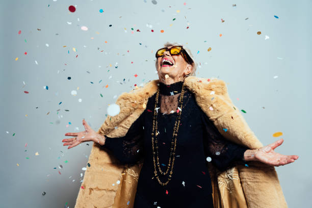 image of a beautiful and elegant old woman image of a beautiful and elegant old influencer woman. Cool grandmother posing in studio wearing fashionable clothes. Confetti explosion on her 90s birthday celebration only senior women stock pictures, royalty-free photos & images