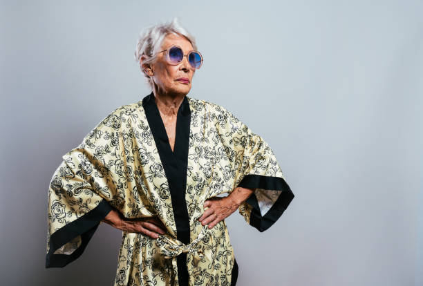 beautiful and elegant old influencer woman. Cool grandmother posing in studio wearing fashionable clothes. Happy senior lady celebrating and making party. Concept about seniority and lifestyle