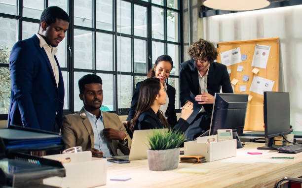 istock Diverse and multiracial smart businesspeople wearing formal suits, using computer, working, meeting, brainstorming together about company marketing plan or creative idea in indoor modern office. 1357726218