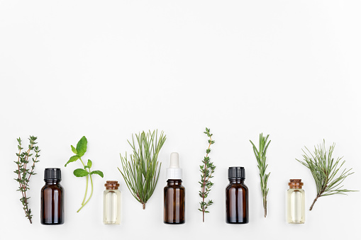 Bottles of rosemary, pine, thyme, mint essential oil on a white background, top view, copy space