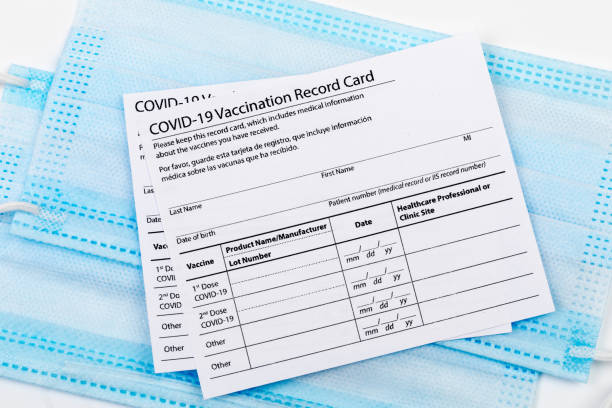 istock Coronavirus vaccination record card. Protective mask divided into two parts. Concept of defeating Covid-19 1357732608