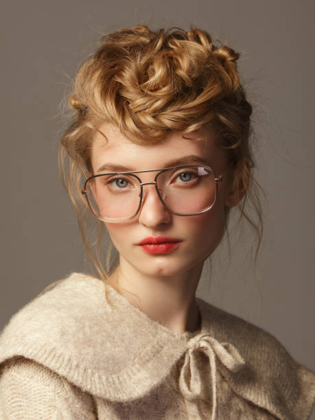 Young beautiful woman with eyeglasses Portrait of young beautiful woman with eyeglasses and wearing knitted beige sweater, retro style nerd sweater stock pictures, royalty-free photos & images