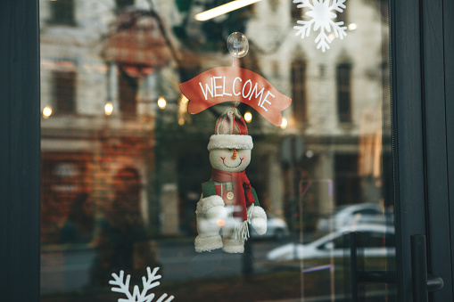Christmas decoration on the door of the cafe with the inscription Welcome. Celebrating Christmas, New Year and festive concept.
