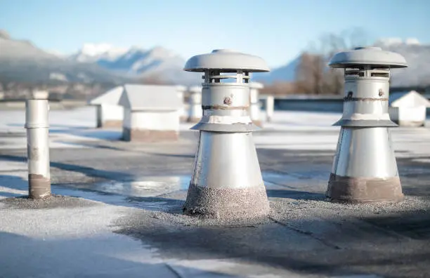 Photo of Set of flat roof ventilators on building with modified bitumen roofing system.