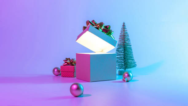 istock Neon xmas winter background. Open Christmas gift box with shine lights, minimal tree. Holiday decoration bauble ball on neon abstract gradient backdrop. Happy new year copy space. 1357737745