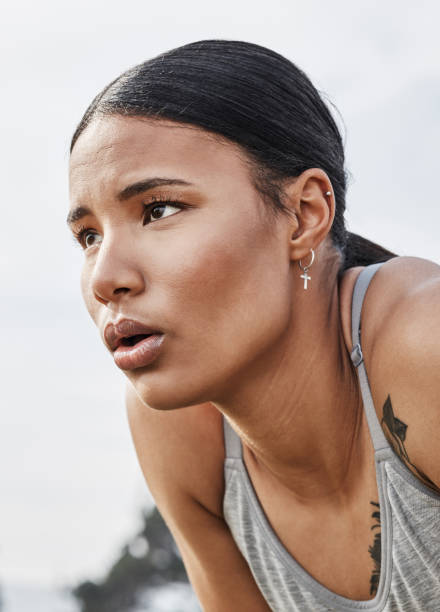 shot of a young woman catching her breath while exercising outdoors - playing field effort outdoors human age imagens e fotografias de stock