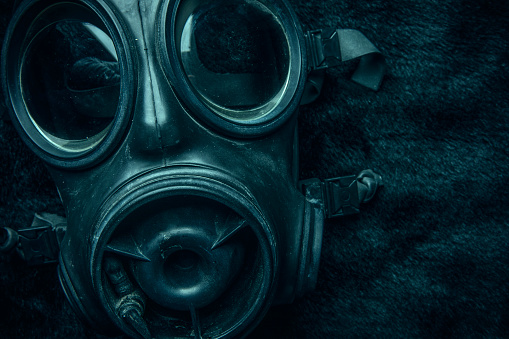 A close up of a creepy gas mask on black with a poisonous green tint.