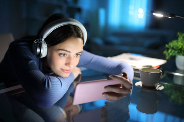 Woman watching media on smart phone in the night at home stock photo