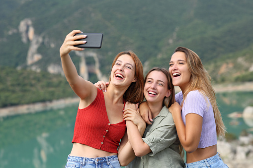 Funny friends taking selfies on smartphone in the mountain
