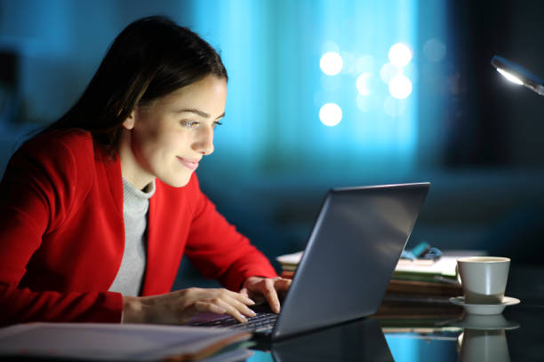 Happy woman using laptop in the night at home