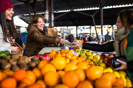 A mature woman farmer is smiling while serving her customers