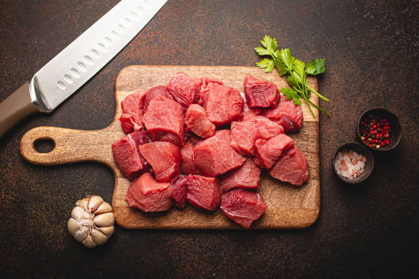Beef raw meat cubes for stew on wooden cutting board