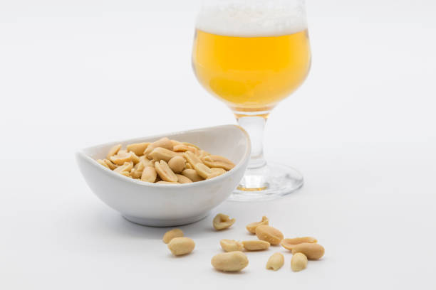 bowl with peeled peanuts and one beer - beer nuts imagens e fotografias de stock